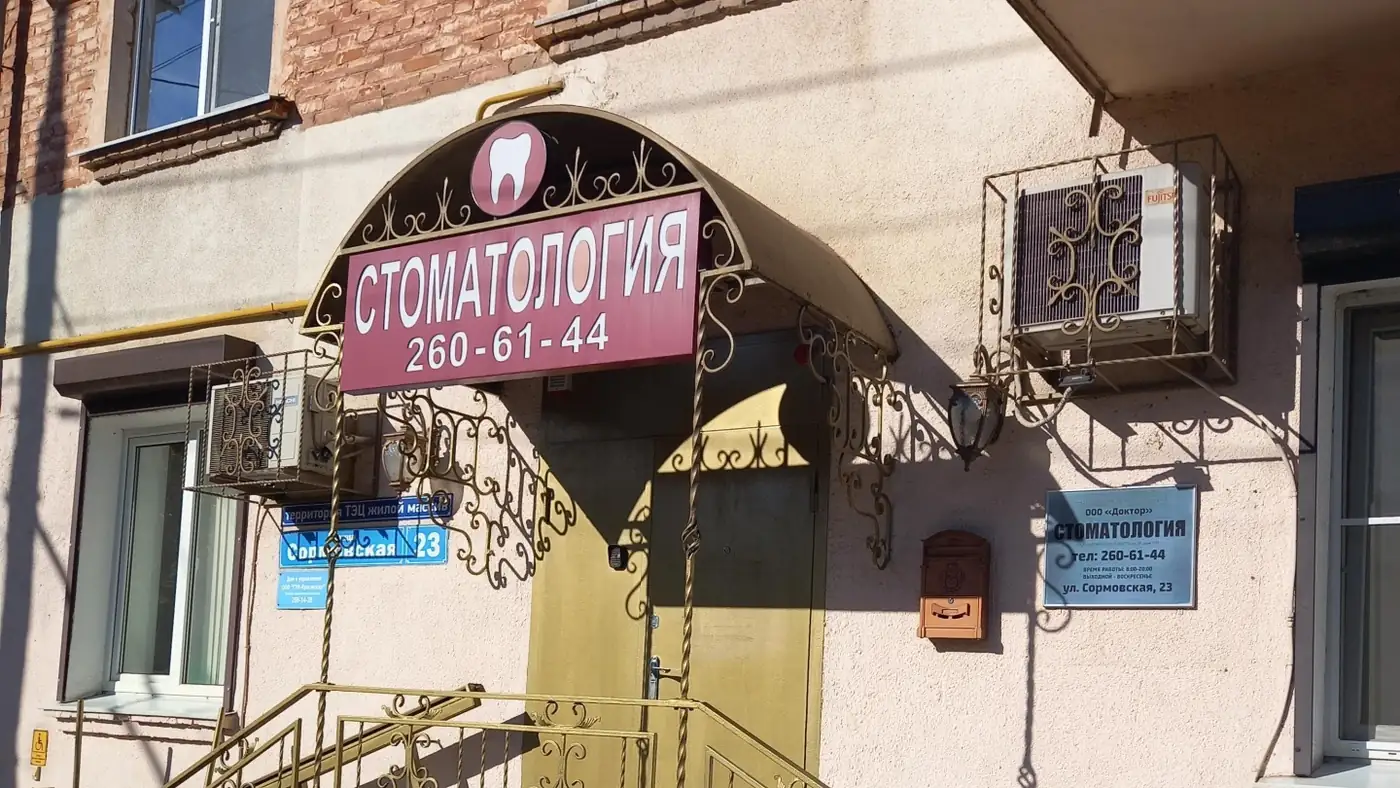 Вход в стоматологическую клинику «Доктор» с вывеской и табличкой на фасаде дома на Сормовской улице